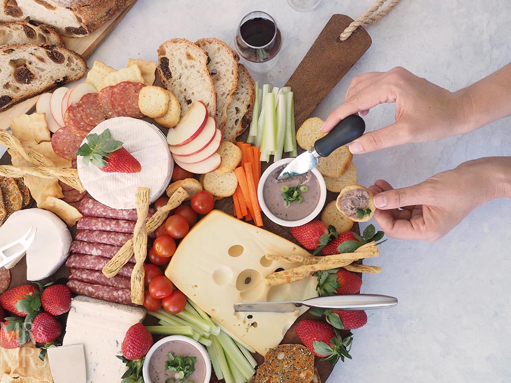 Port and Gorgonzola pate recipe - pate on a big cheese platter with someone scooping some pate from the ramekin