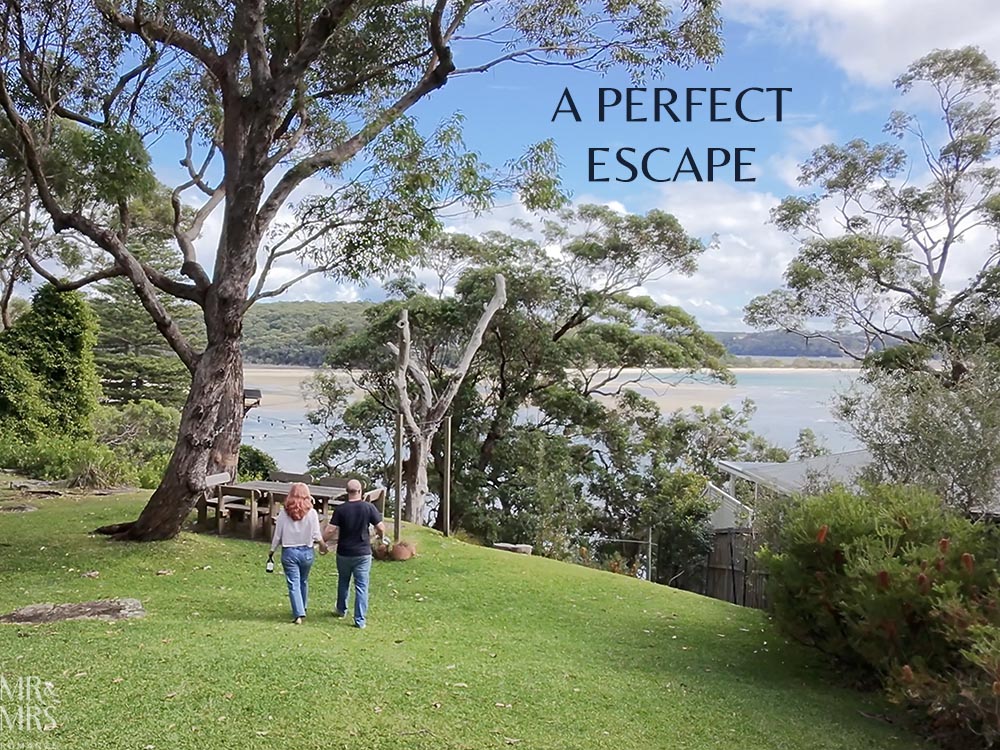 Simpson Cottage Review - Jim & Christina walking down the garden to the outdoor table. View out over the bay